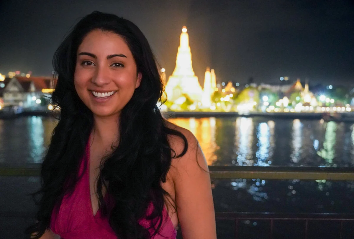 a woman standing in front of a temple in Bangkok at night