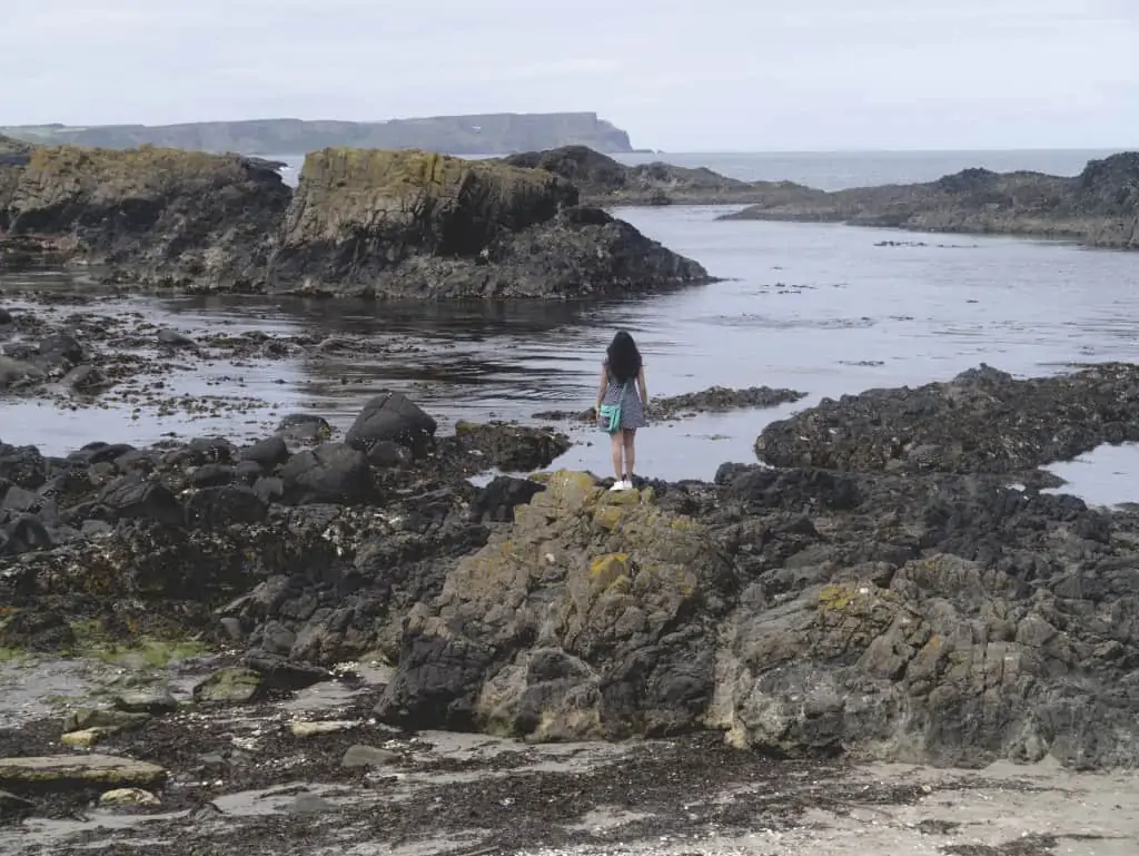 a girl standing on rocks on the coast