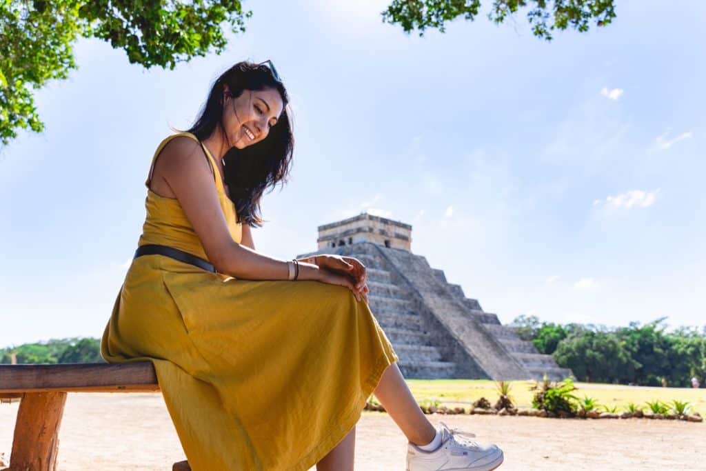 a girl sitting in front of Chichen Itza in Mexico