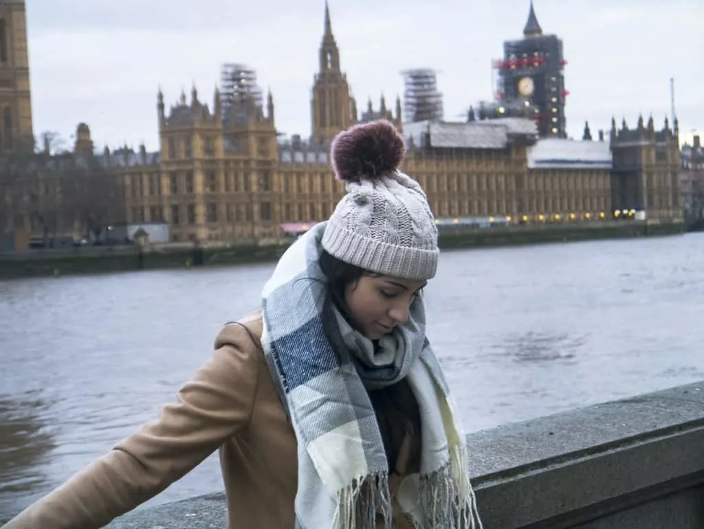 a girl standing in front of the River Thames and the Parliament Building in London