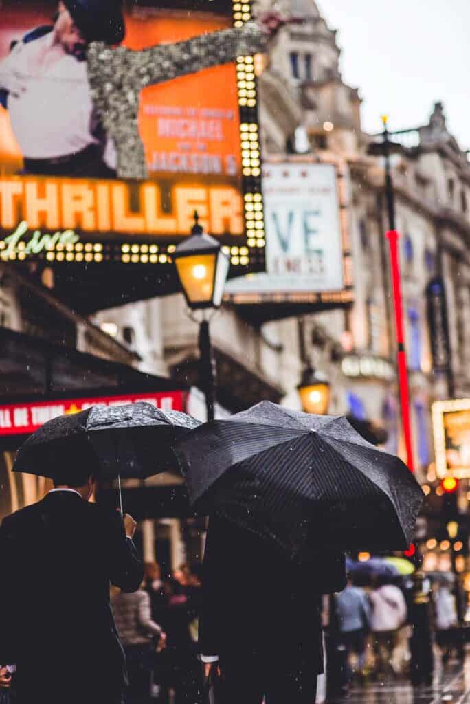 two men walking in the rain by the theatre in London