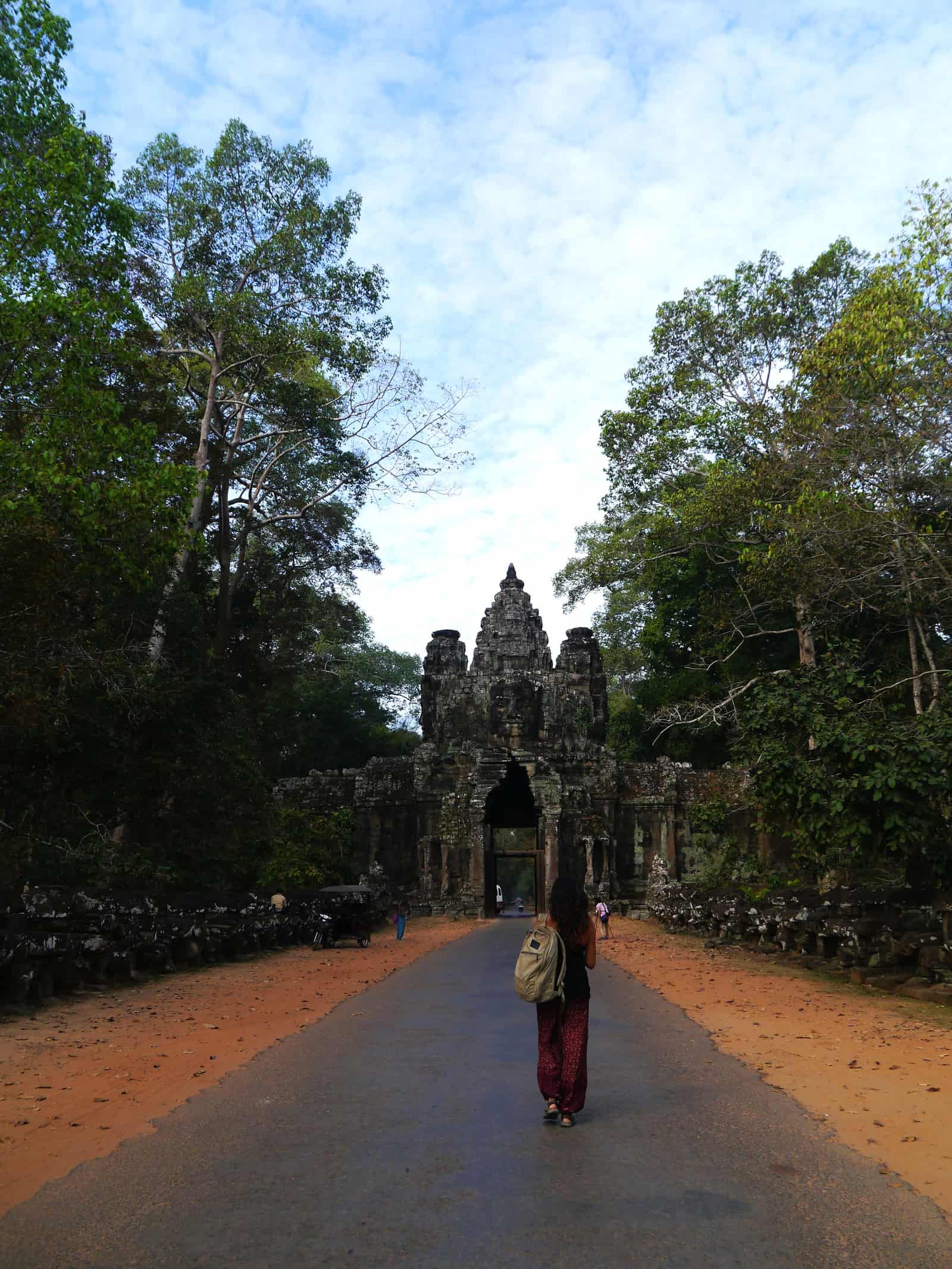 a woman walking toward Angkor Wat temple in the morning
