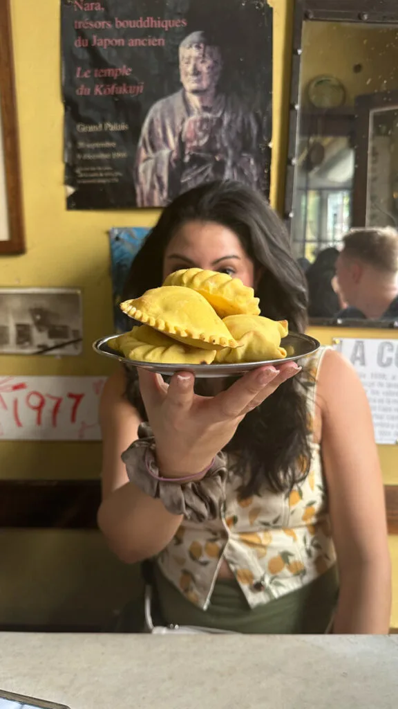 a woman holding a plate of empanadas on a food tour in Argentina